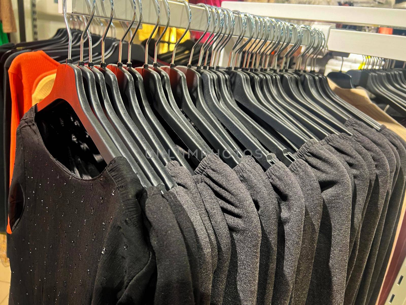 clothes on a rack in a store. Wardrobe with same black dresses and t-shirts by Suietska