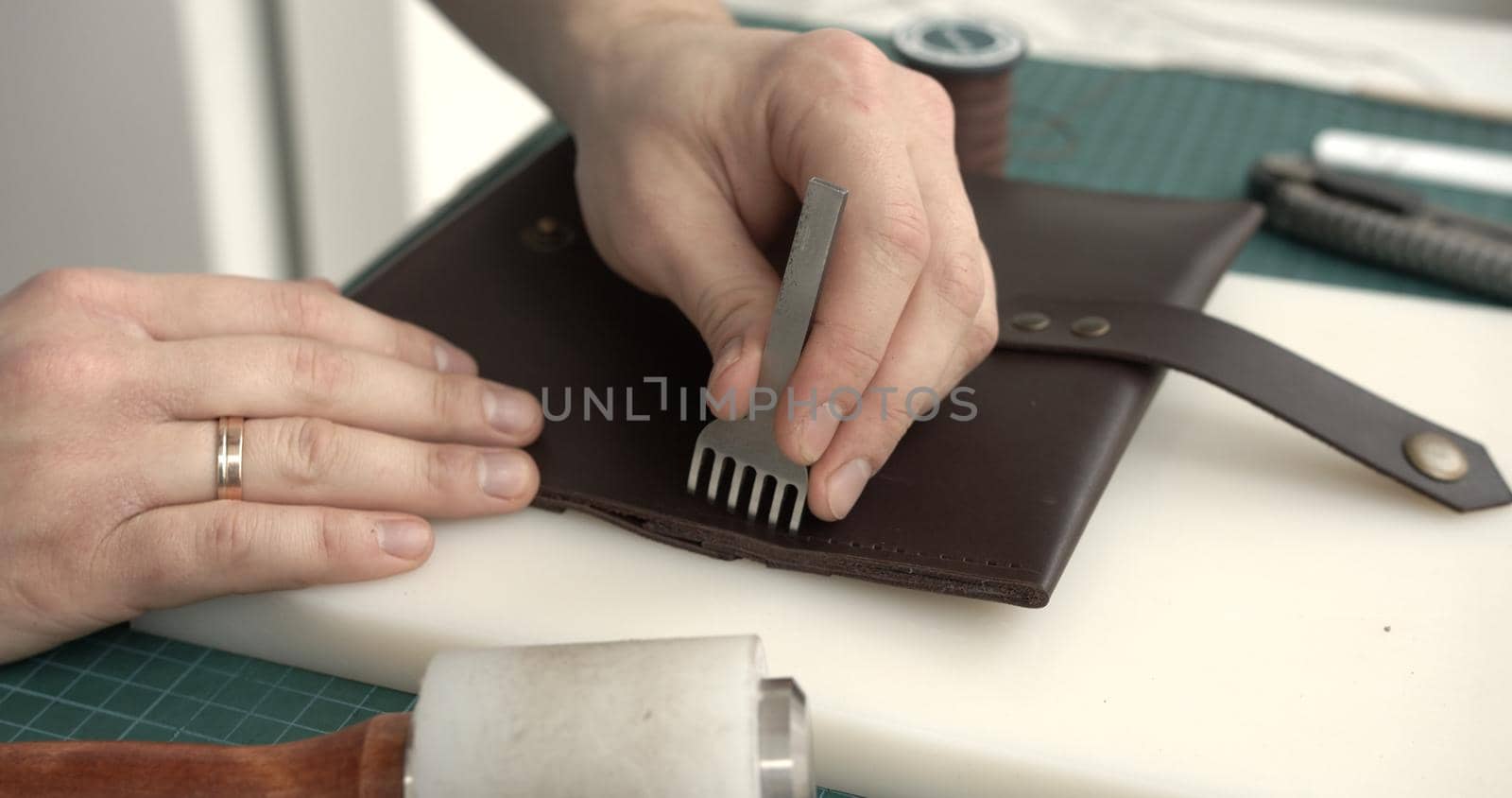 Making of brown handmade leather wallet. Sewing wallet. Piercer punches holes in a piece of skin