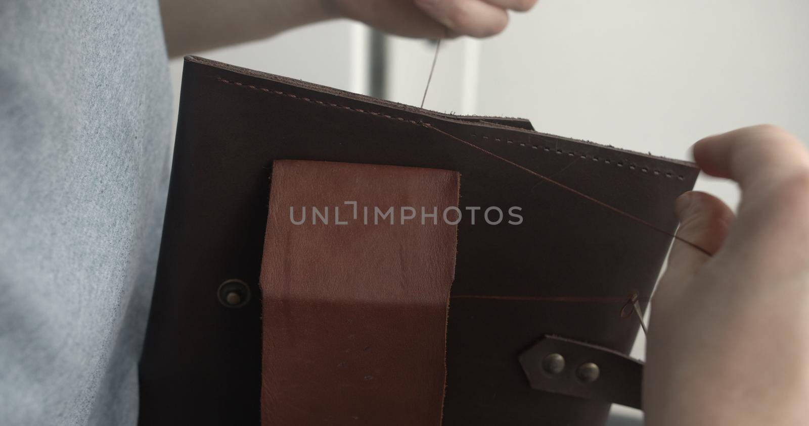 Making a handmade brown leather wallets. The hands of the master sew a leather product. by vovsht