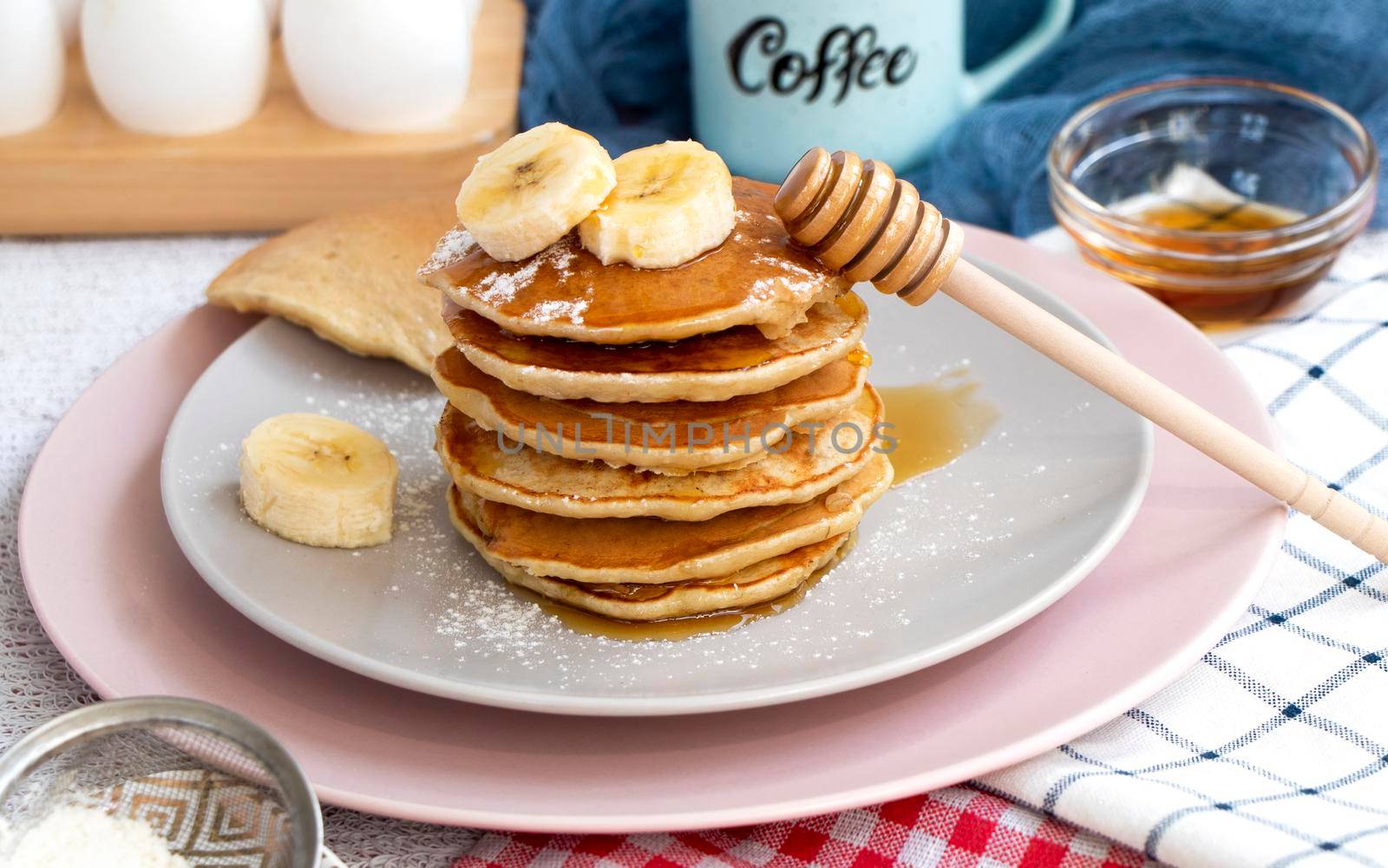 Pour maple syrup over homemade banana cupcakes. A slide of hot cupcakes with fresh bananas on a plate. Maple serop sprouts over cupcakes. Portion of breakfast on a plate. High quality photo