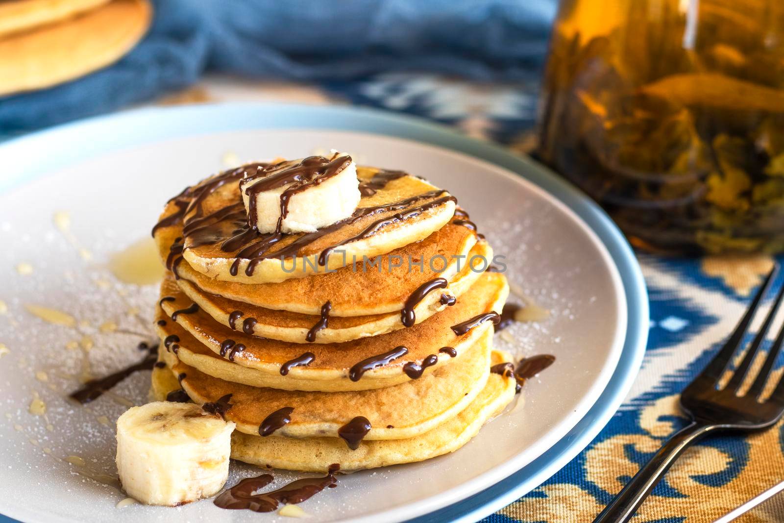 classic american breakfast. homemade banana pancakes on plate sprinkled powder and honey. A slide of hot pancakes with fresh bananas on a plate on the kitchen table . Pancake slide with honey topping