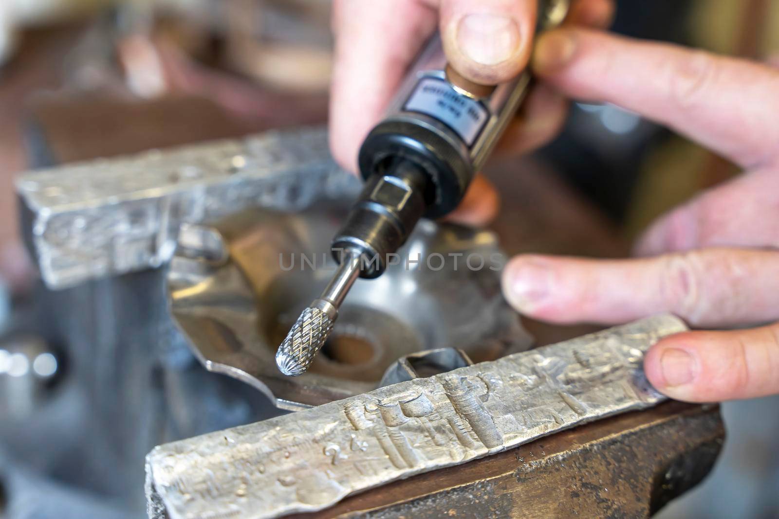 the master processes the part with a milling cutter using a pneumatic grinding machine. Car service, workshop. Car repair. repair of motorcycles and motors. repair tools