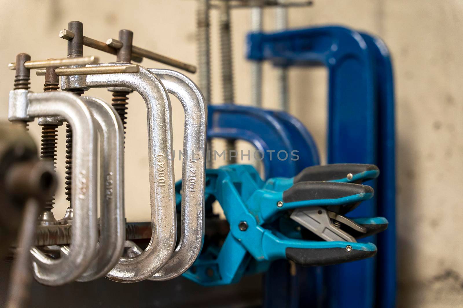 mechanical hand clamps on the welding table in the auto and motorcycle repair shop. A series of C - shaped metal clips