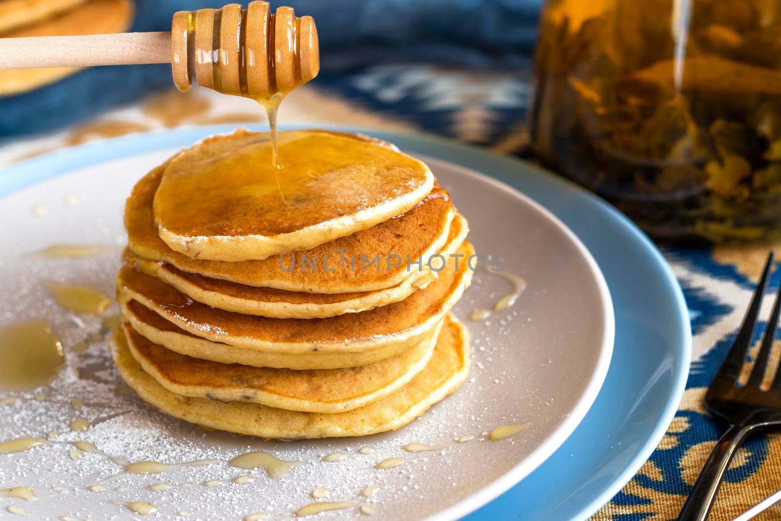 classic american breakfast. homemade banana pancakes on plate sprinkled powder and honey. Pancakes on the kitchen table . Pancake slide with honey topping . High quality photo