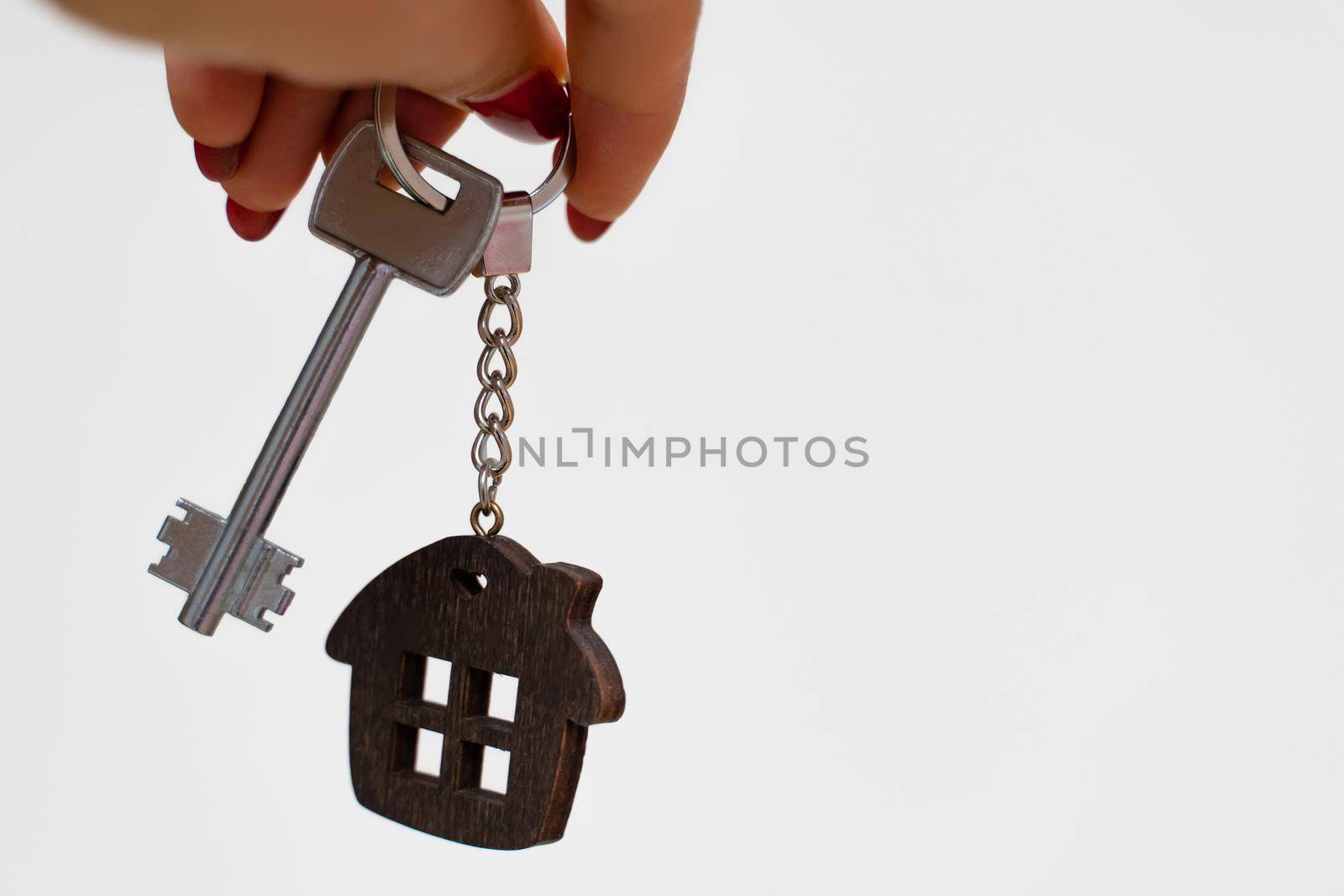 A woman's hand holds a house key on a white background with copy space. Real estate agent. Buying a house, apartment