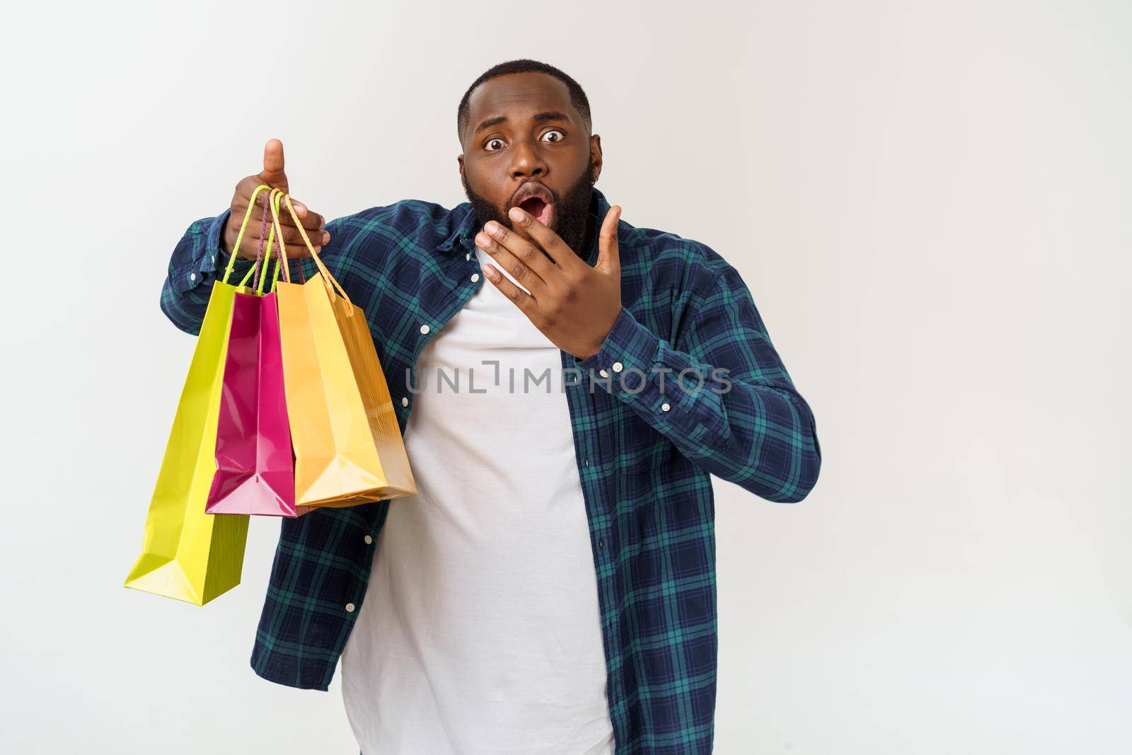 Happy african american man holding shopping bags on white background. Holidays concept by Benzoix