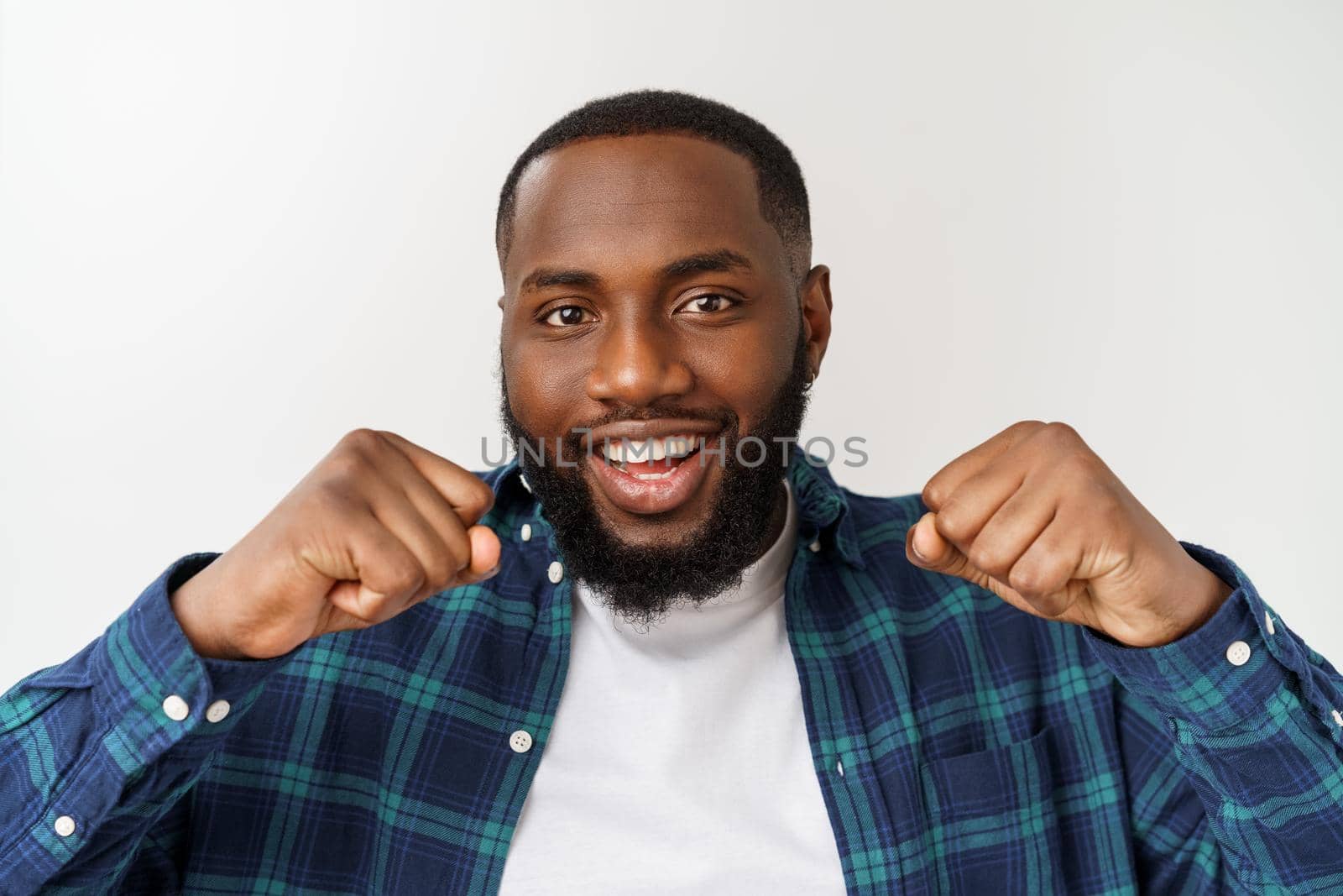 Portrait of a cheerful young man shouting with arms raised in success.