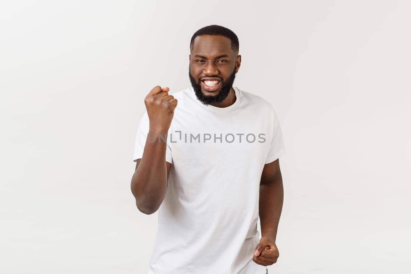 Portrait of a cheerful young man shouting with arms raised in success by Benzoix