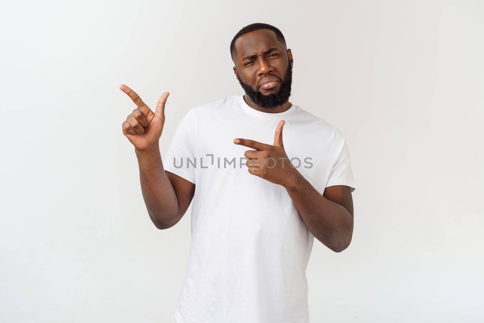 Young amazed African American pointing his finger at white background with copy space for your advertisement by Benzoix