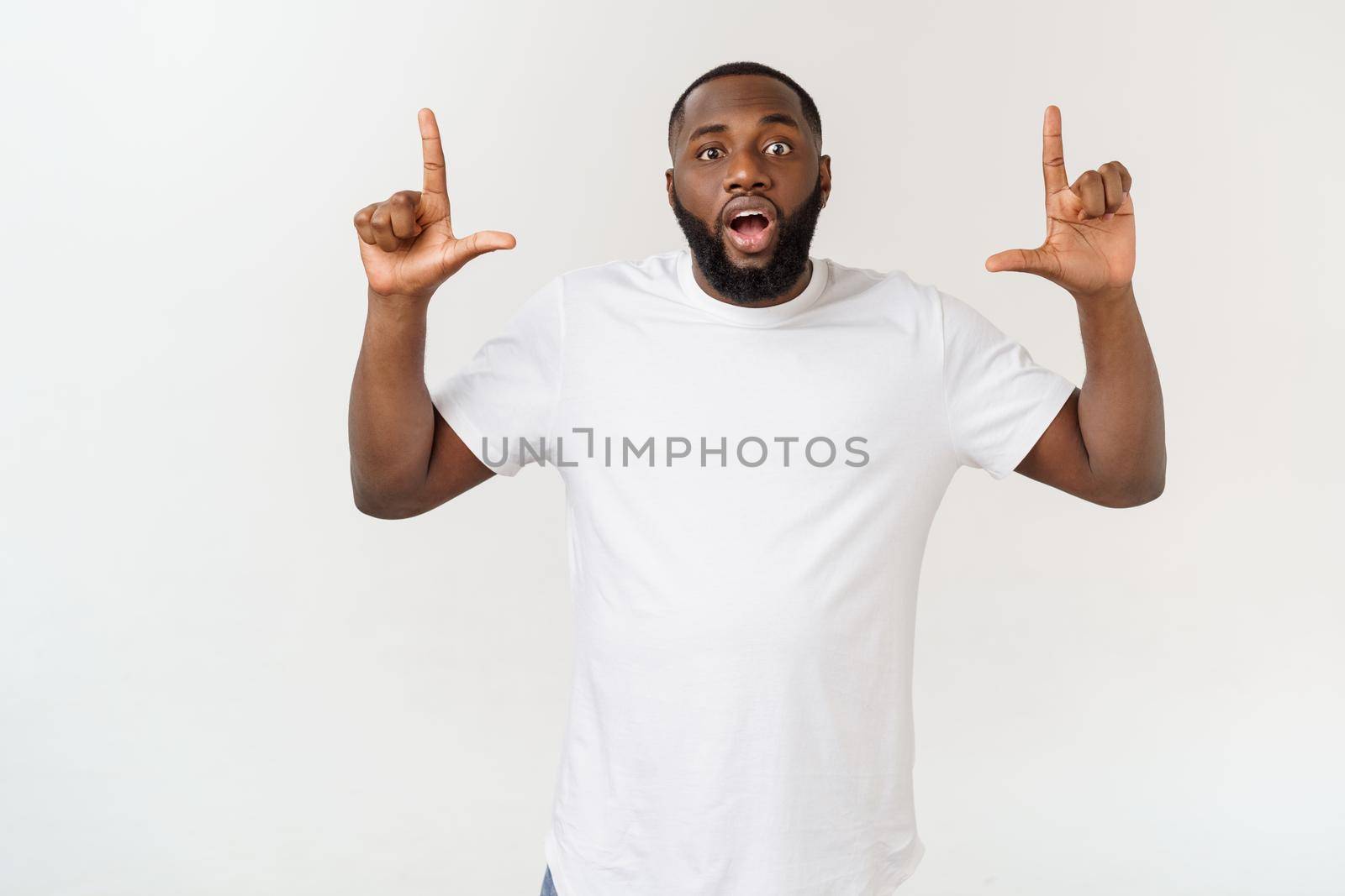 Young amazed African American pointing his finger at white background with copy space for your advertisement.