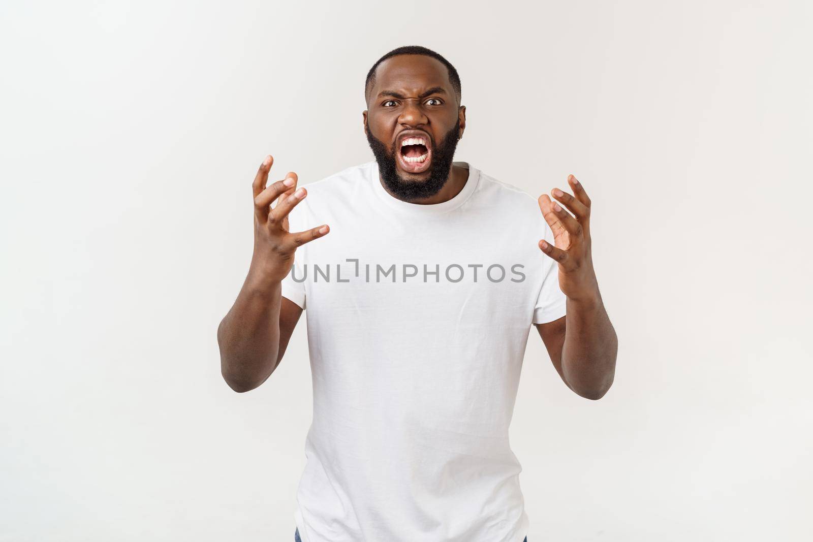 Portrait of shocked young African American man wearing white blank T-shirt looking at the camera in surprise, stunned with some incredible story. by Benzoix