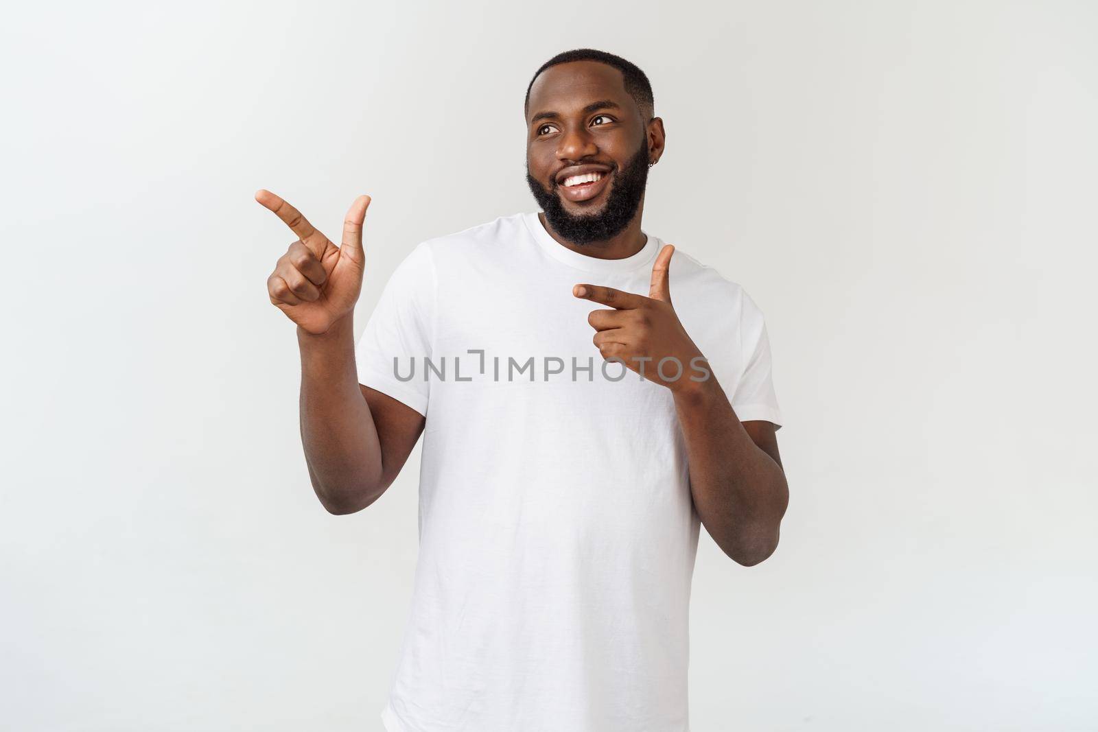 Young amazed African American pointing his finger at white background with copy space for your advertisement by Benzoix