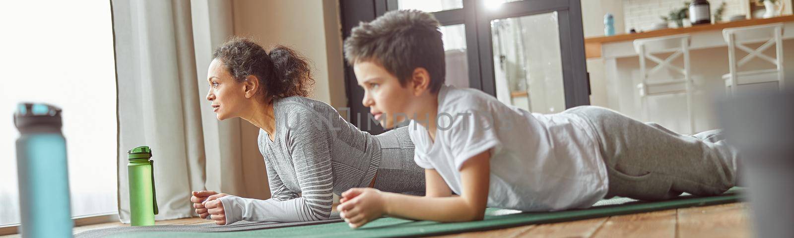 Sporty mom training core with son at home by Yaroslav_astakhov