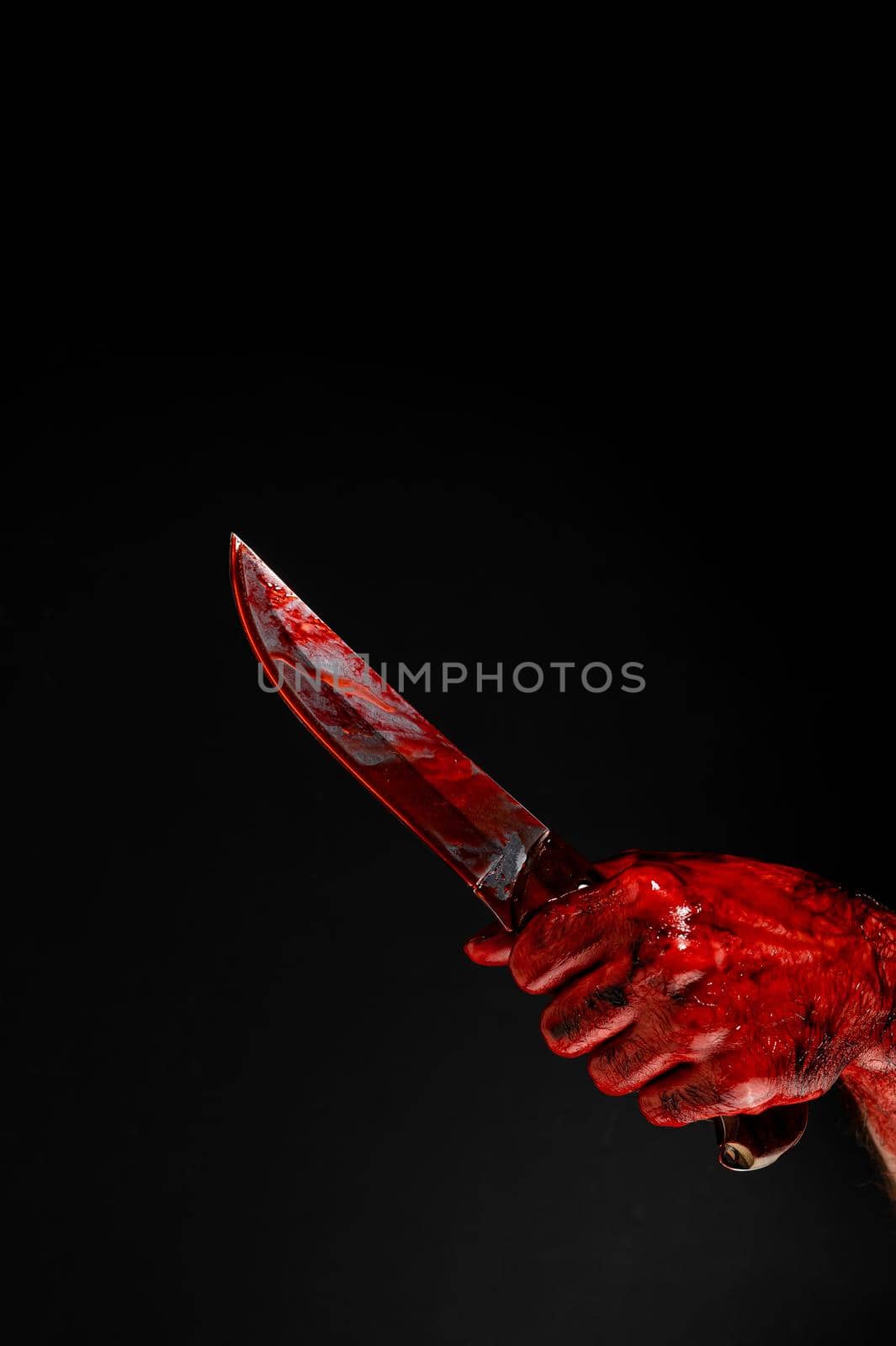 A man with bloody hands brandishes a knife on a black background