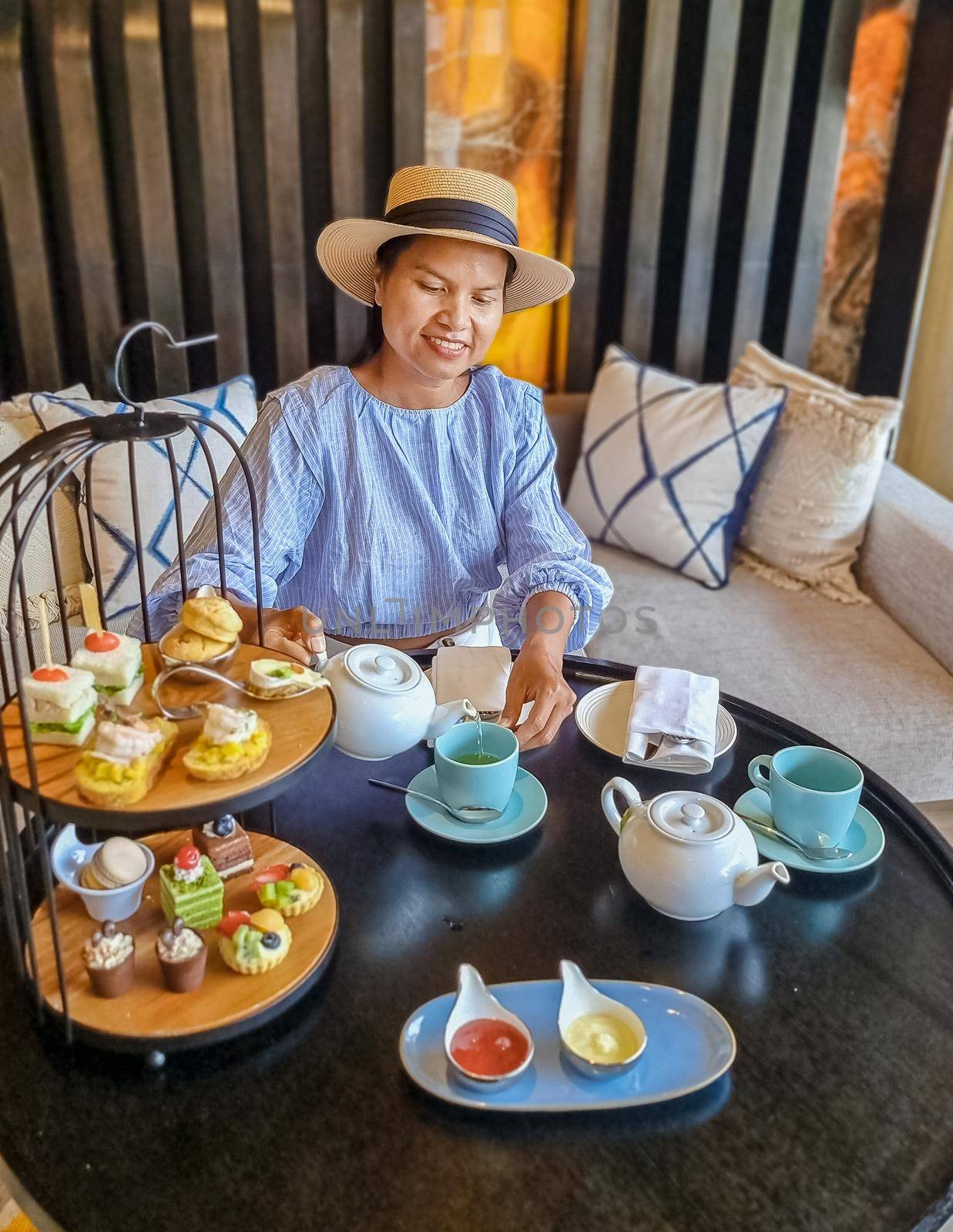 Asian women having a Luxury high tea with snack and tea in a luxury hotel by fokkebok