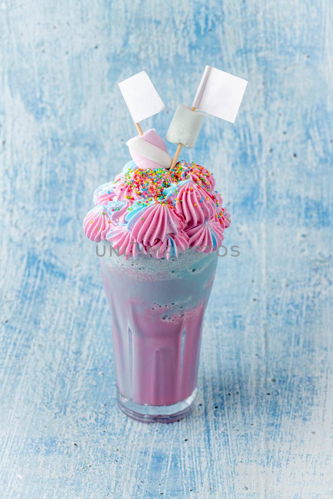 Blue and pink milkshake decorated with marshmallows on a blue background. by Sonat