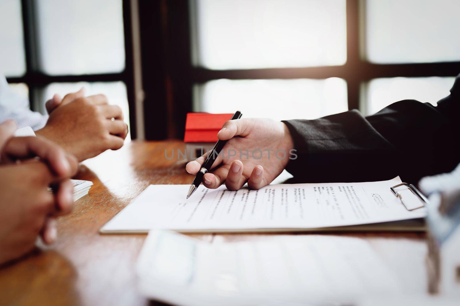 A couple is reading a home purchase contract before signing documents with a real estate agent.