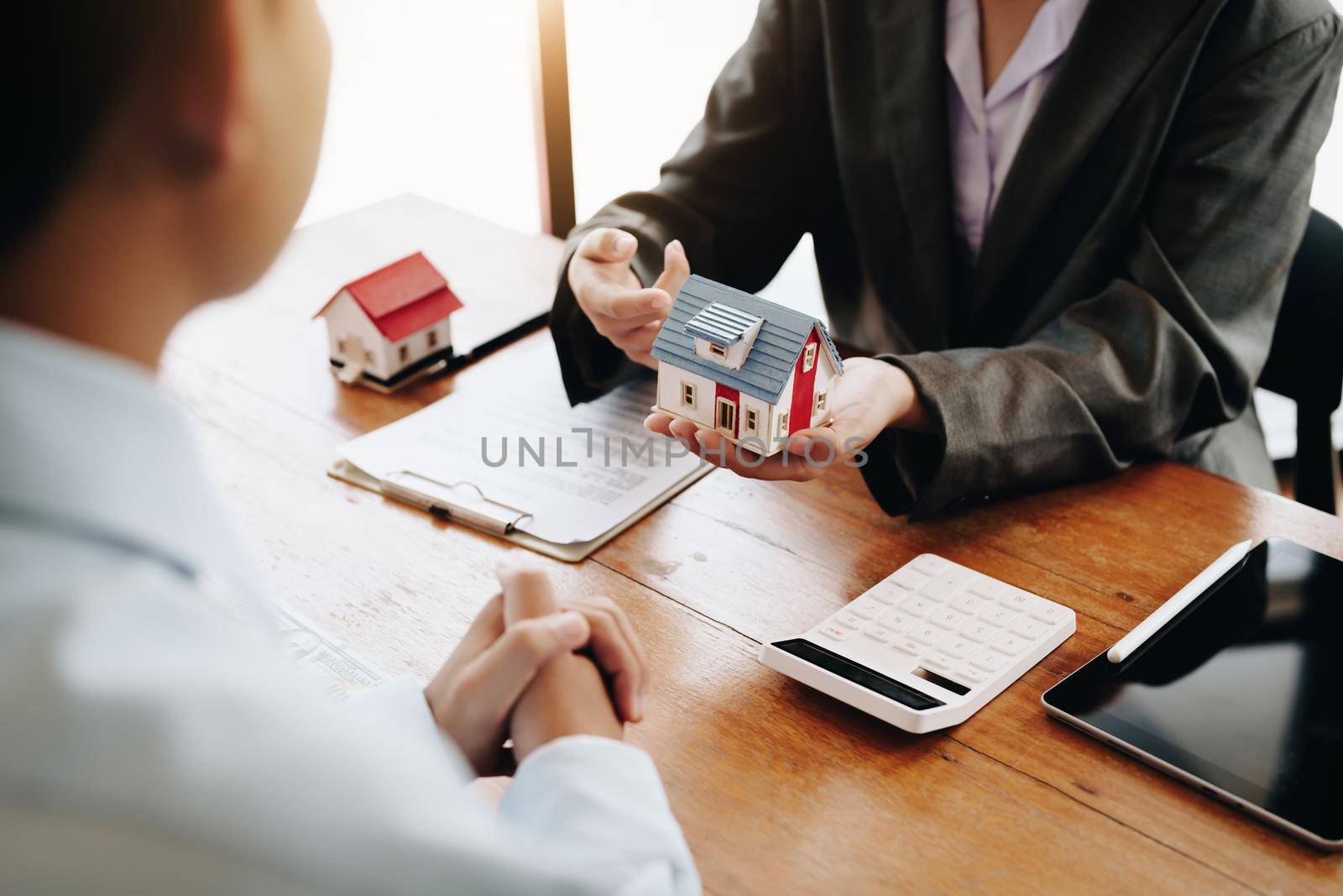 The real estate agent is showing the house model to the customer.