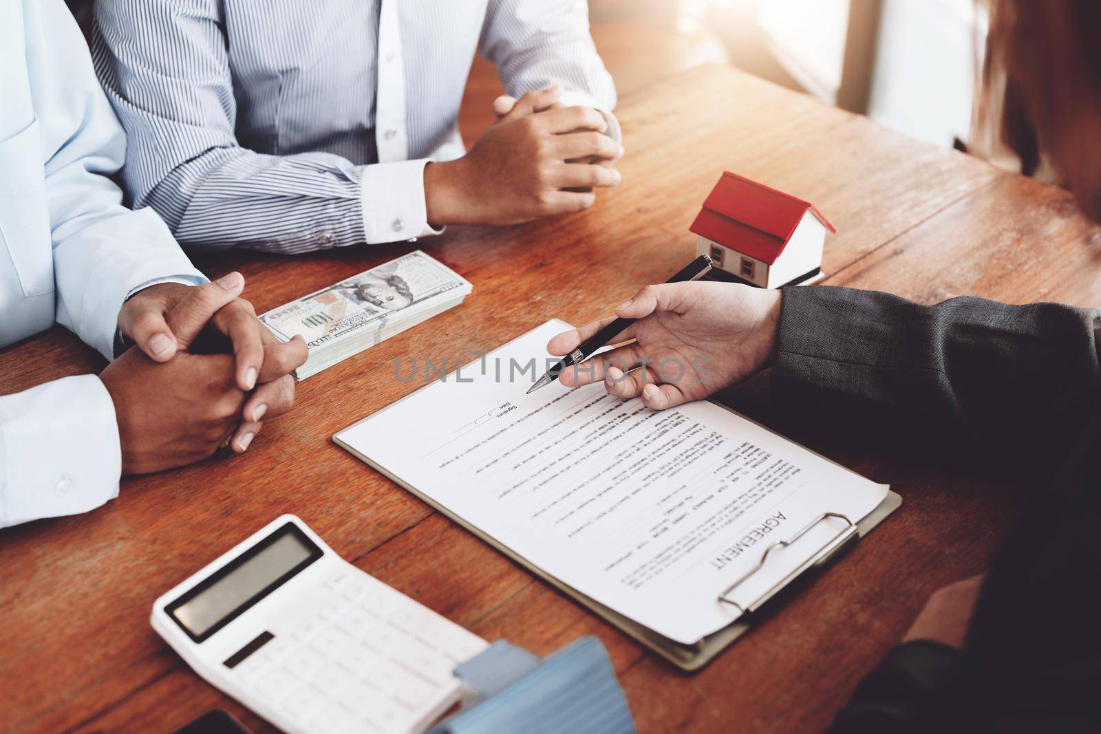 A couple is reading a home purchase contract before signing documents with a real estate agent.