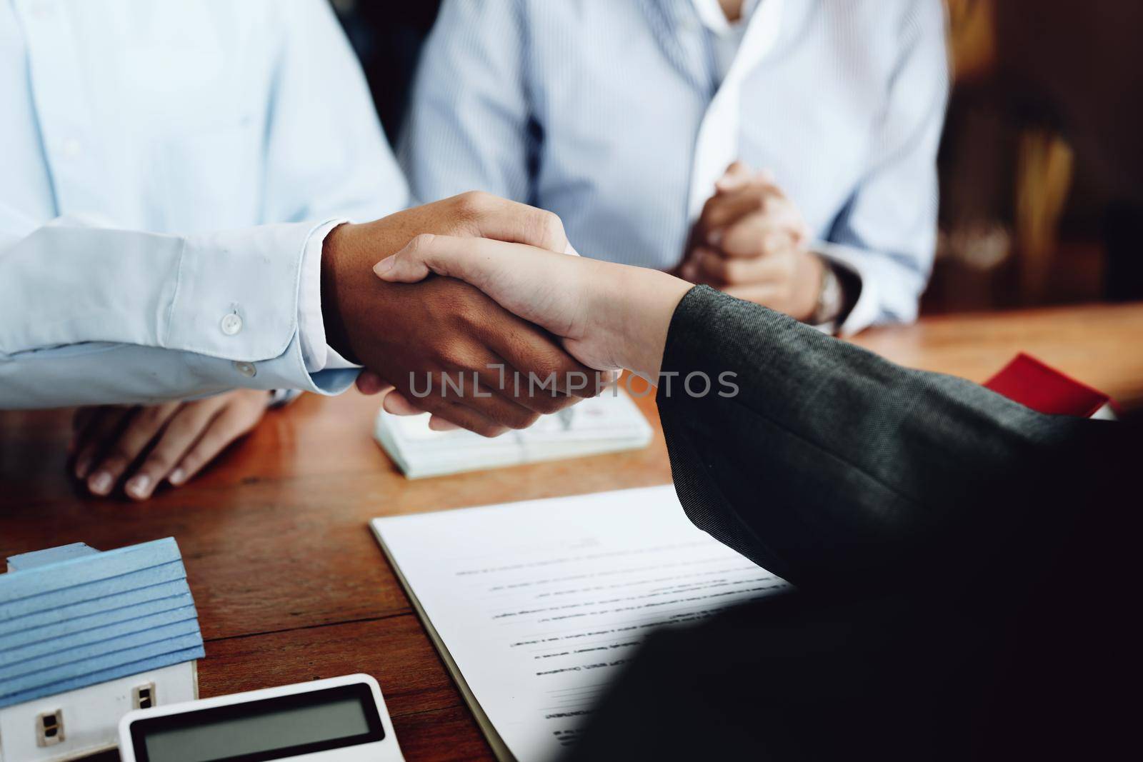 Real estate agents shake hands with customers after signing documents.