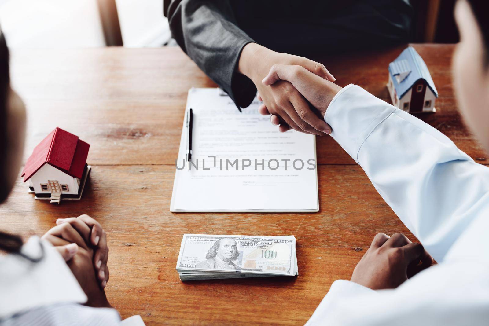 Real estate agents shake hands with customers after signing documents.