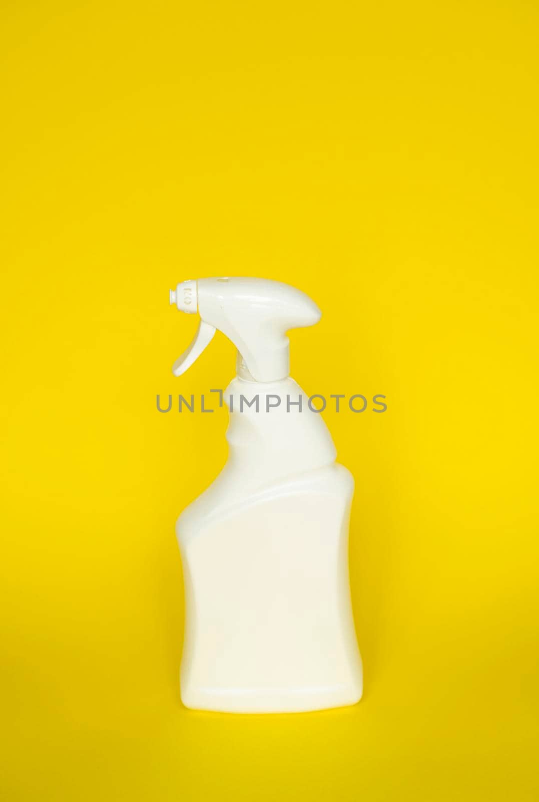 White detergent bottles or chemical cleaning supplies with a sprayer isolated on yellow background