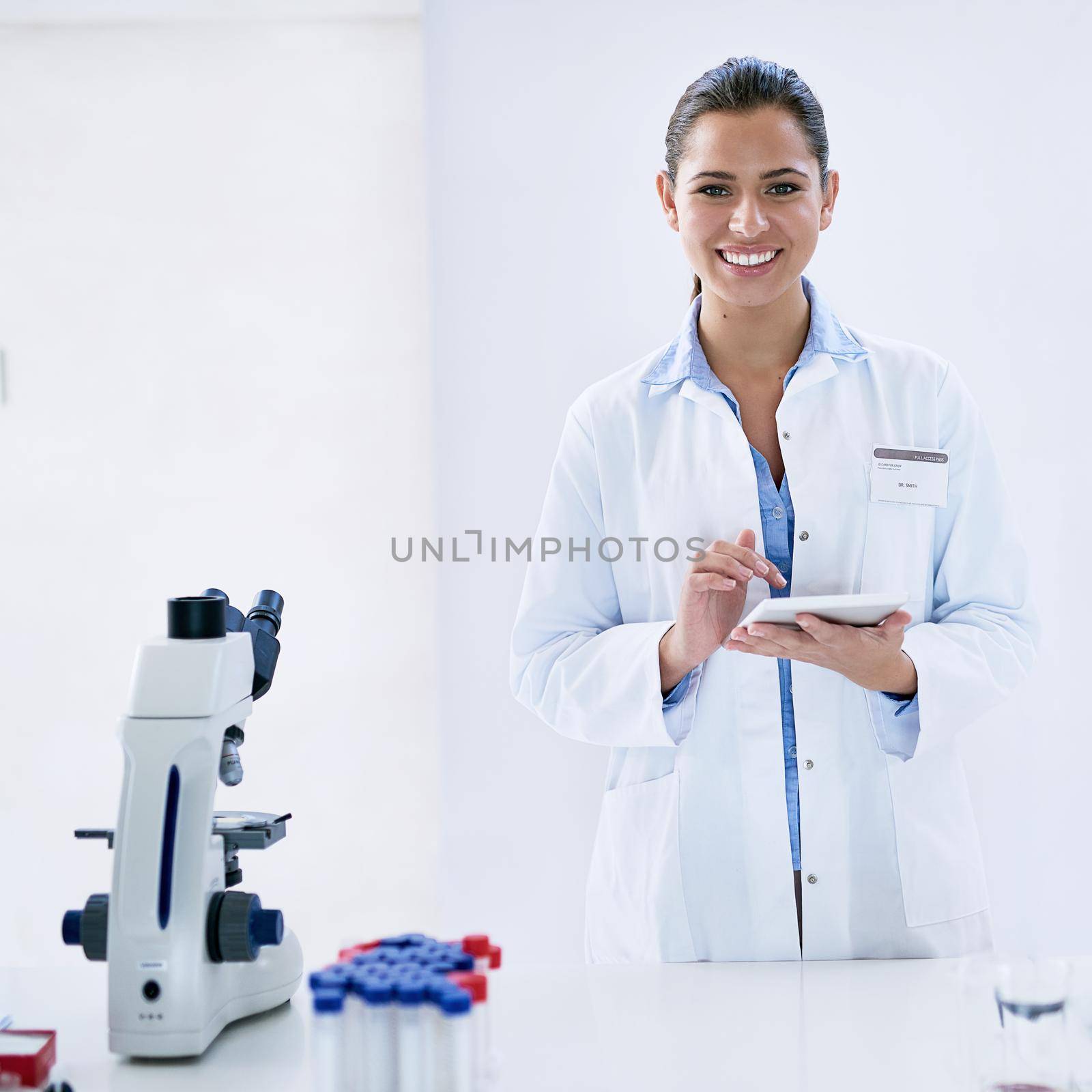 Technology is a vital tool for every researcher. Portrait of a young female scientist working in a lab. by YuriArcurs