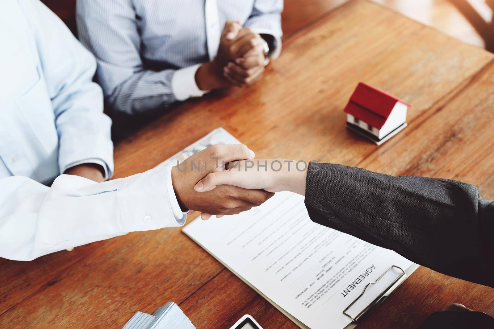 Real estate agents shake hands with customers after signing documents.