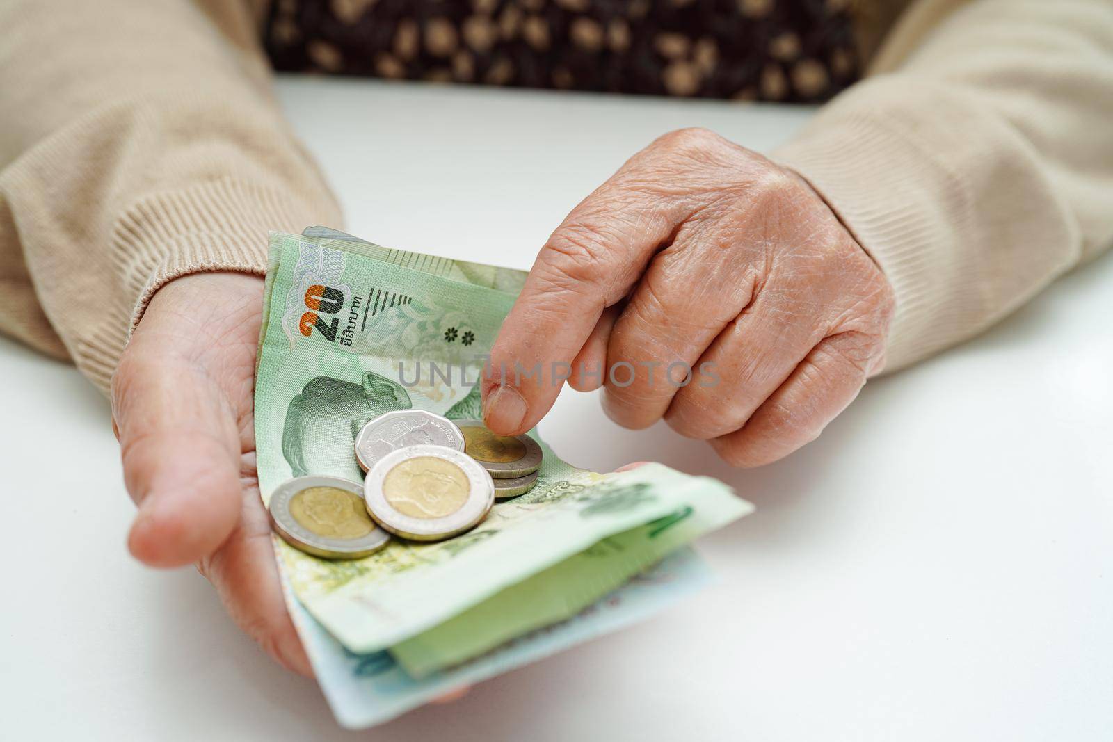 Retired elderly woman counting coins money and worry about monthly expenses and treatment fee payment.