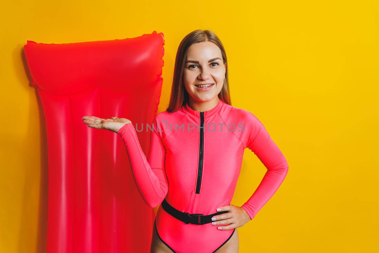 Young woman slim body pink one piece swimsuit on pink air mattress isolated on bright yellow color studio background summer hotel swimming pool sea vacation sun tanning concept. Place for text