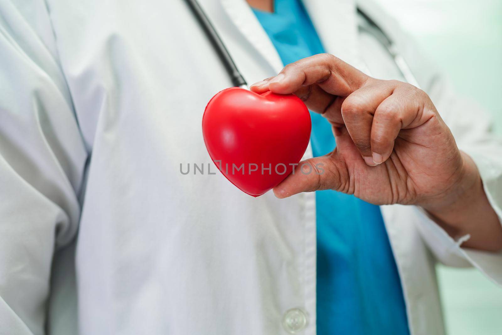 Asian woman doctor holding red heart for health in hospital.