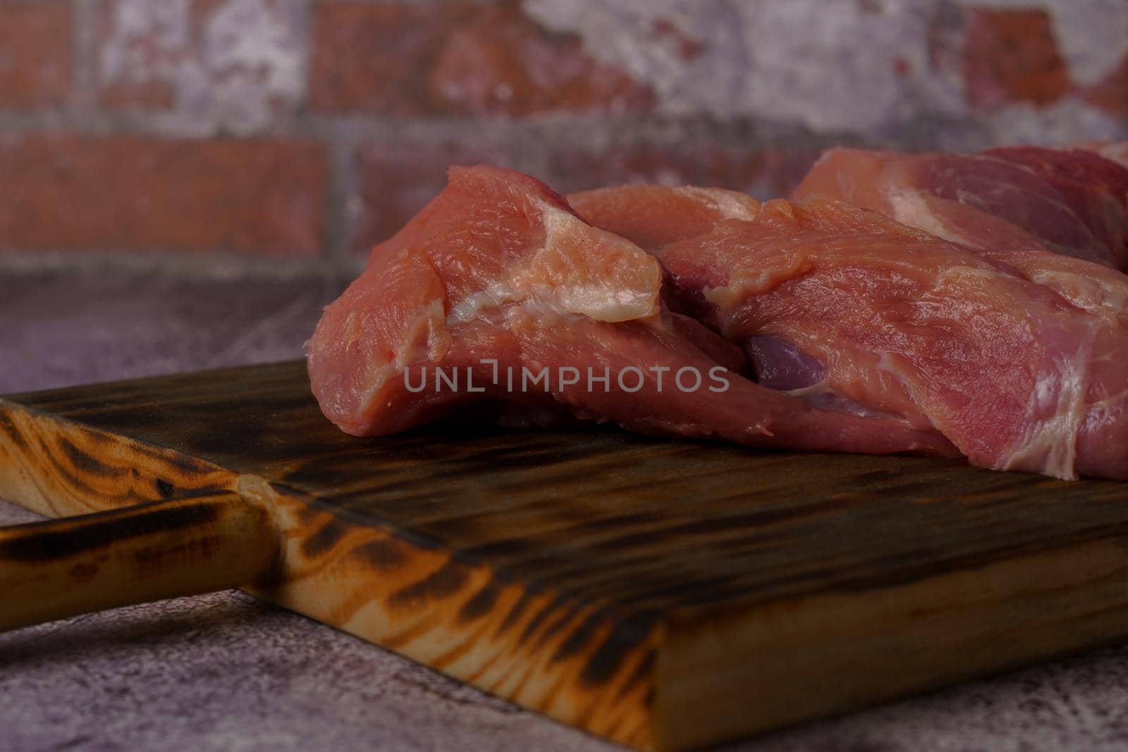 close-up of a filleted raw pork tenderloin on a wooden board