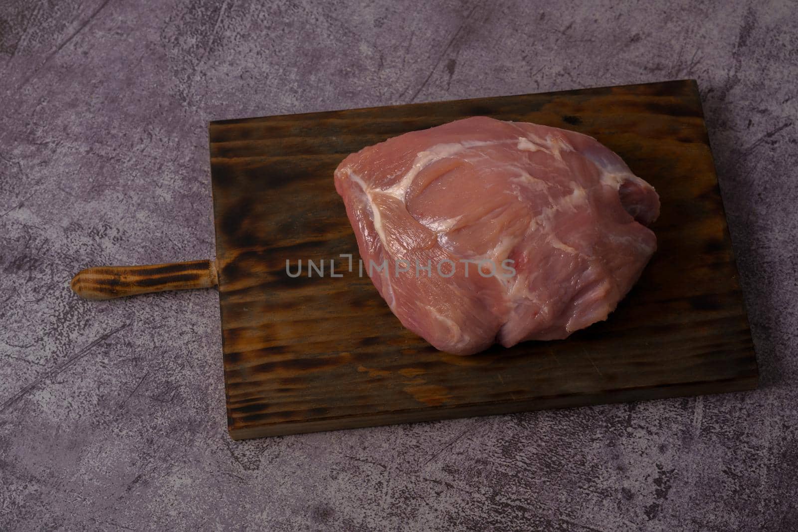 close-up of a piece of raw pork tenderloin on wooden board