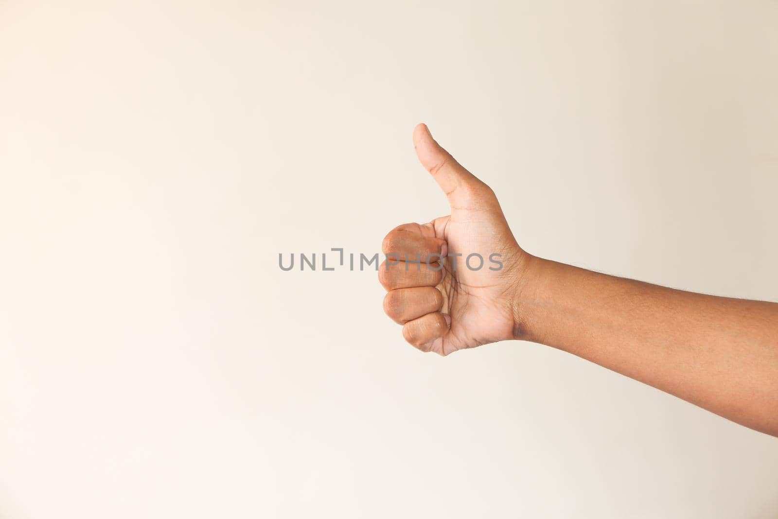 man's hand hand showing a thumb-up on white wall .