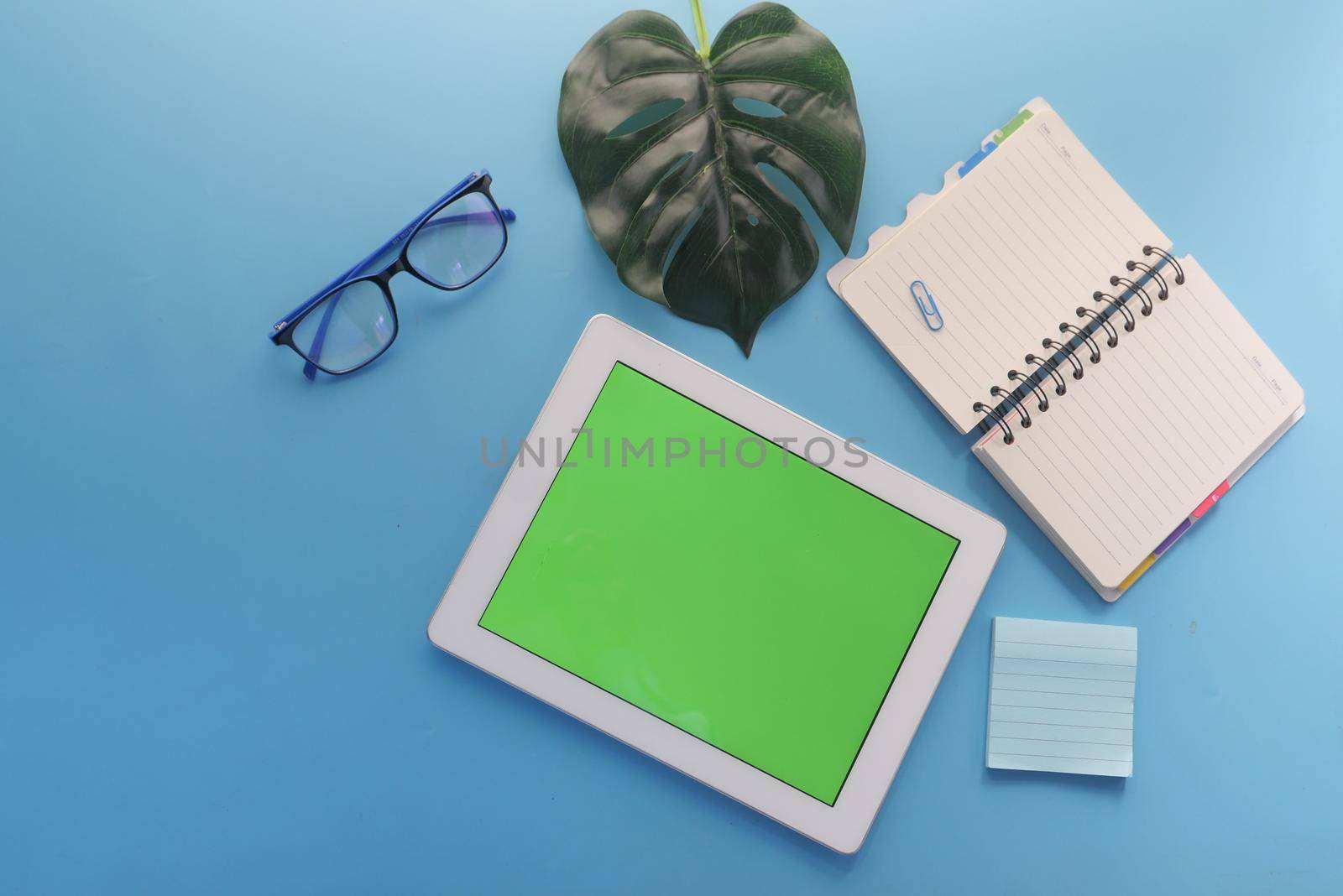 top view of digital tablet with office suppliers on blue background .