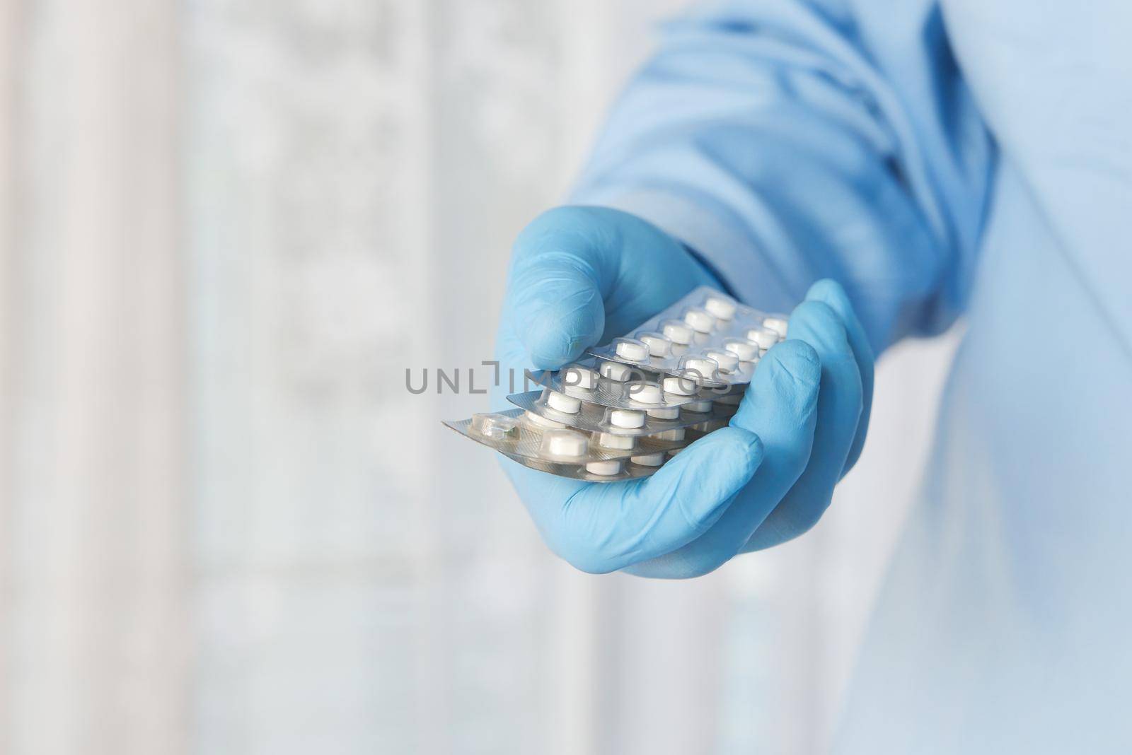 doctor hand in protective glass holding pill container.