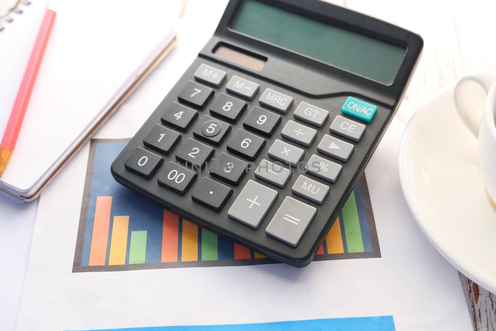 Close up of blue calculator and notepad on color background .