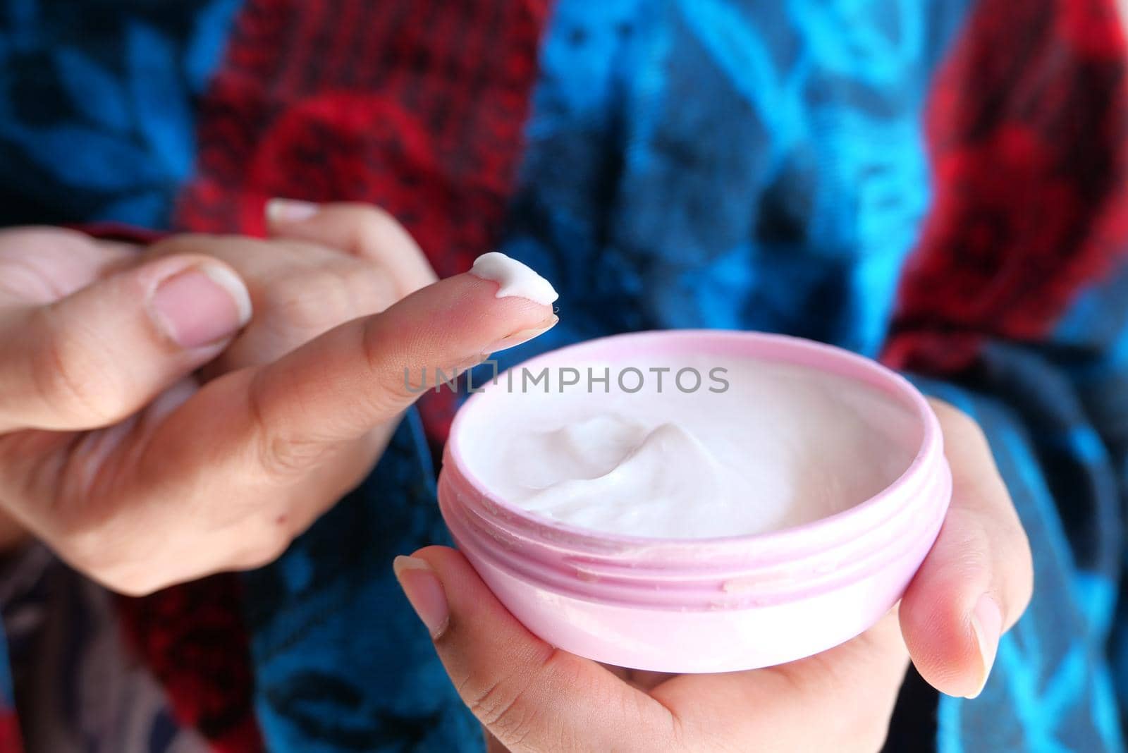woman applying beauty cream onto skin at home top view.