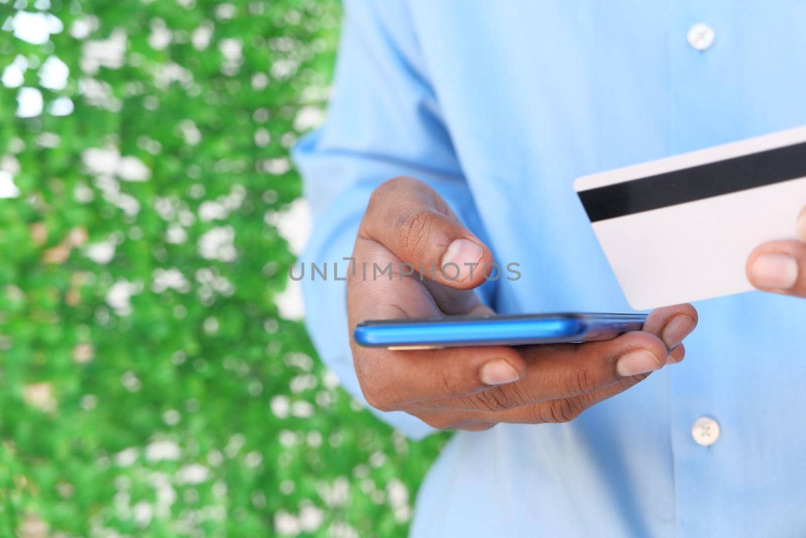 Man hand holding credit card and using smart phone shopping online .