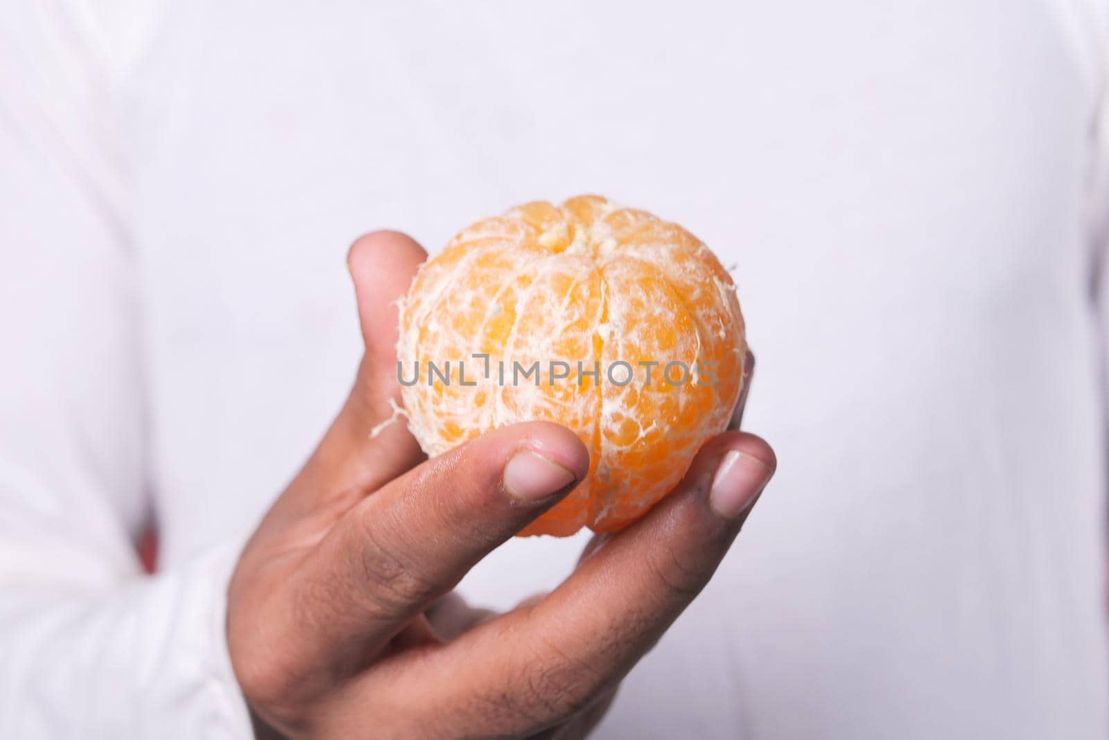 close up of man hand eating slice of orange .