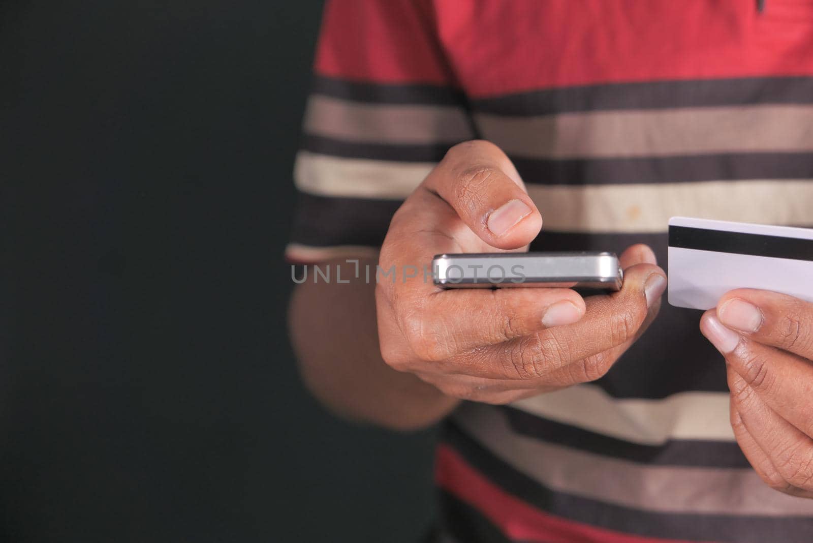 Man hand holding credit card and using smart phone shopping online .