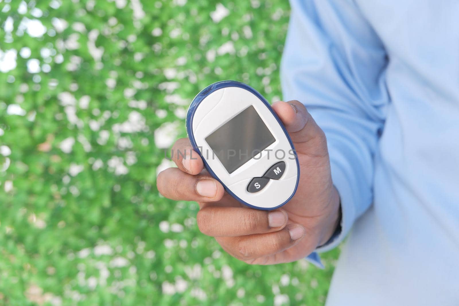 young man holding diabetic measurement tool outdoor with copy space .