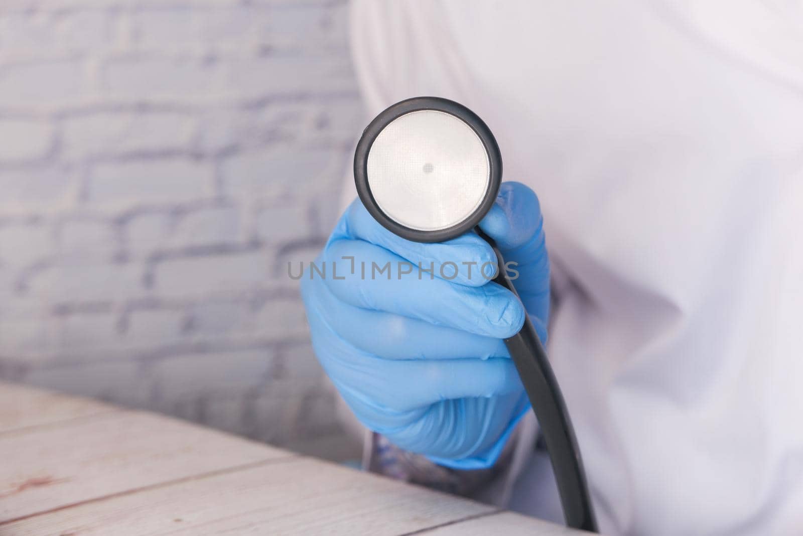doctor hand in protective gloves holding stethoscope .