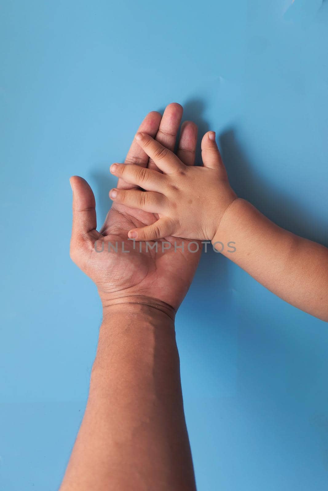 father holding hand of baby child, close up