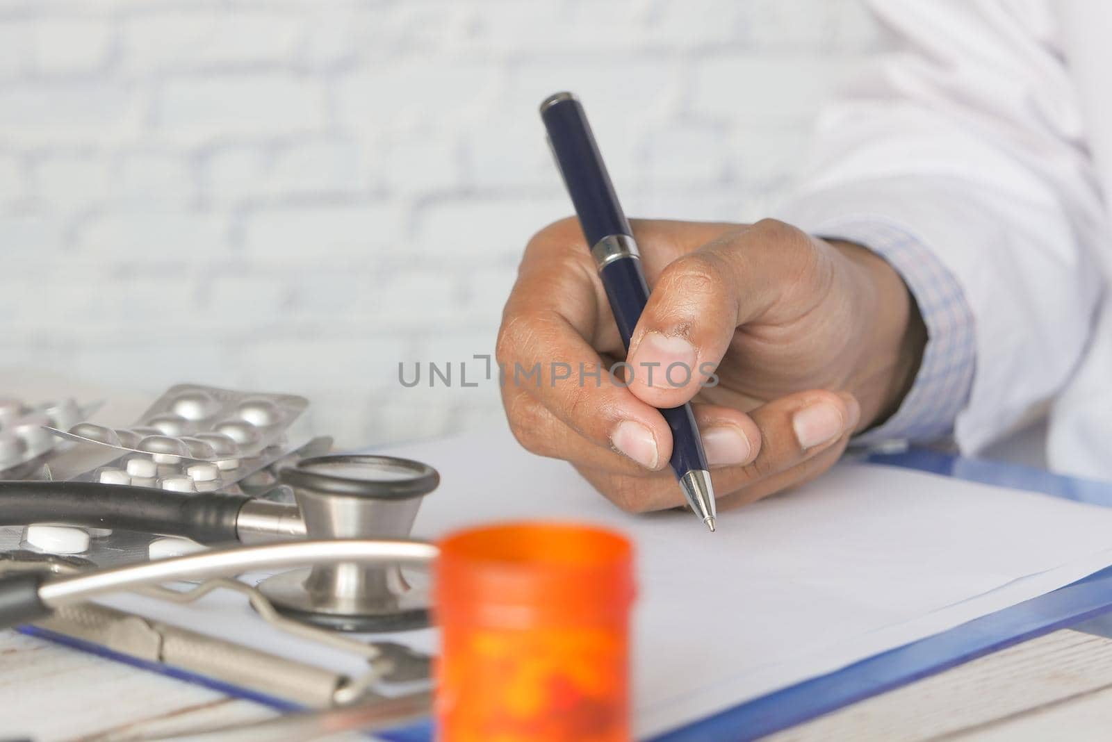 doctor hand writing prescription on clinic desk .
