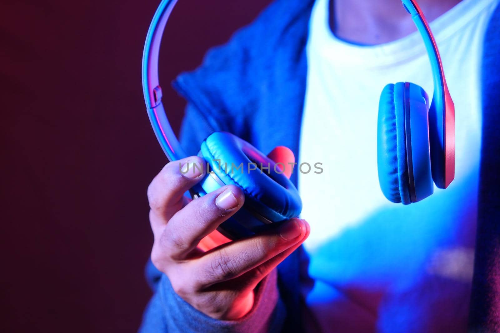 Man hand holding headphone on blue background .
