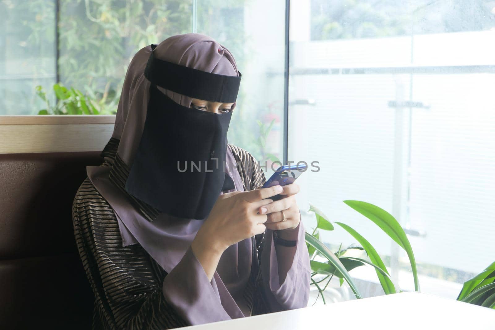 Muslim women with head scarf using smart phone indoor .