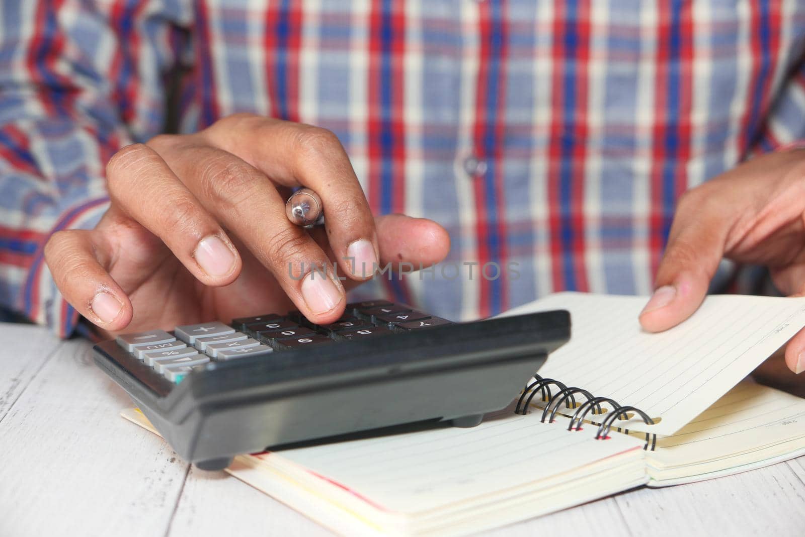 Close up of man hand using calculator.