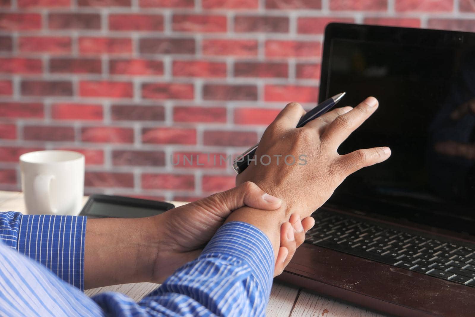 Young man in suffering wrist pain, close up.