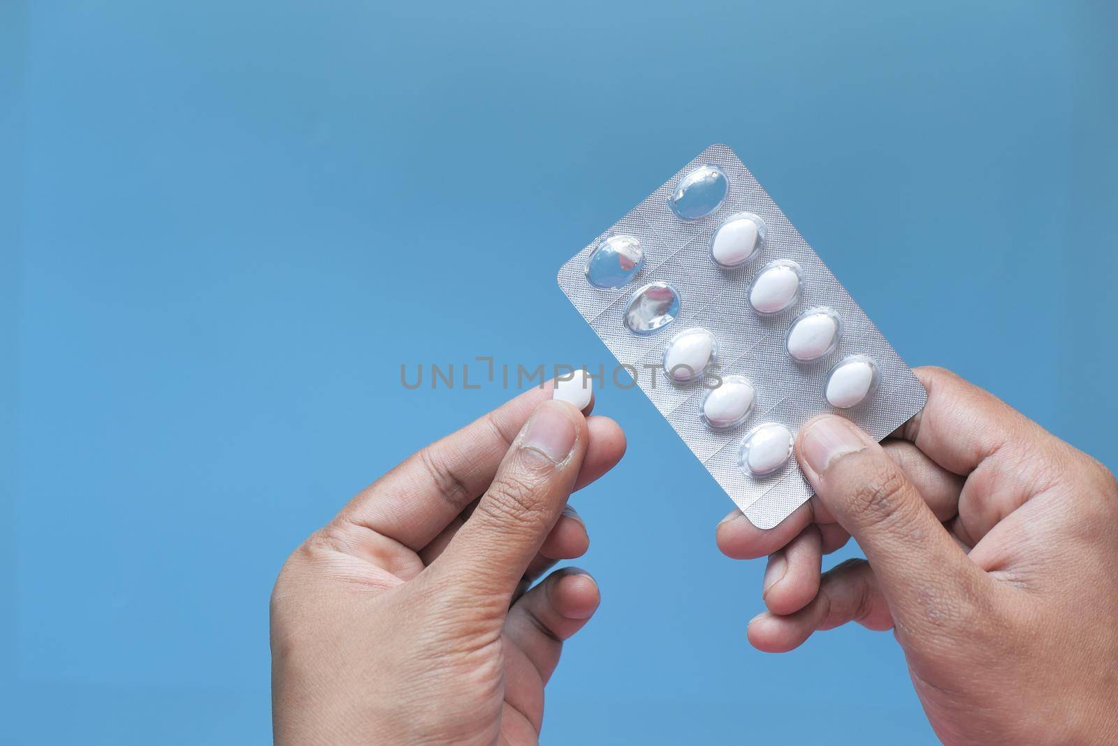 hand holding blister pack isolated on blue .